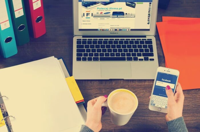 A student relaxing and scrolling through social media and having coffee next to their laptop and binders. Vaia Magazine