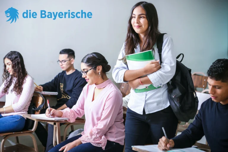 Junge Erwachsene im Klassenzimmer, bereiten sich auf ihre berufliche Zukunft im öffentlichen Dienst vor. Dienstunfähigkeit absichern – das Logo der Bayerischen symbolisiert die Unterstützung und Absicherung.